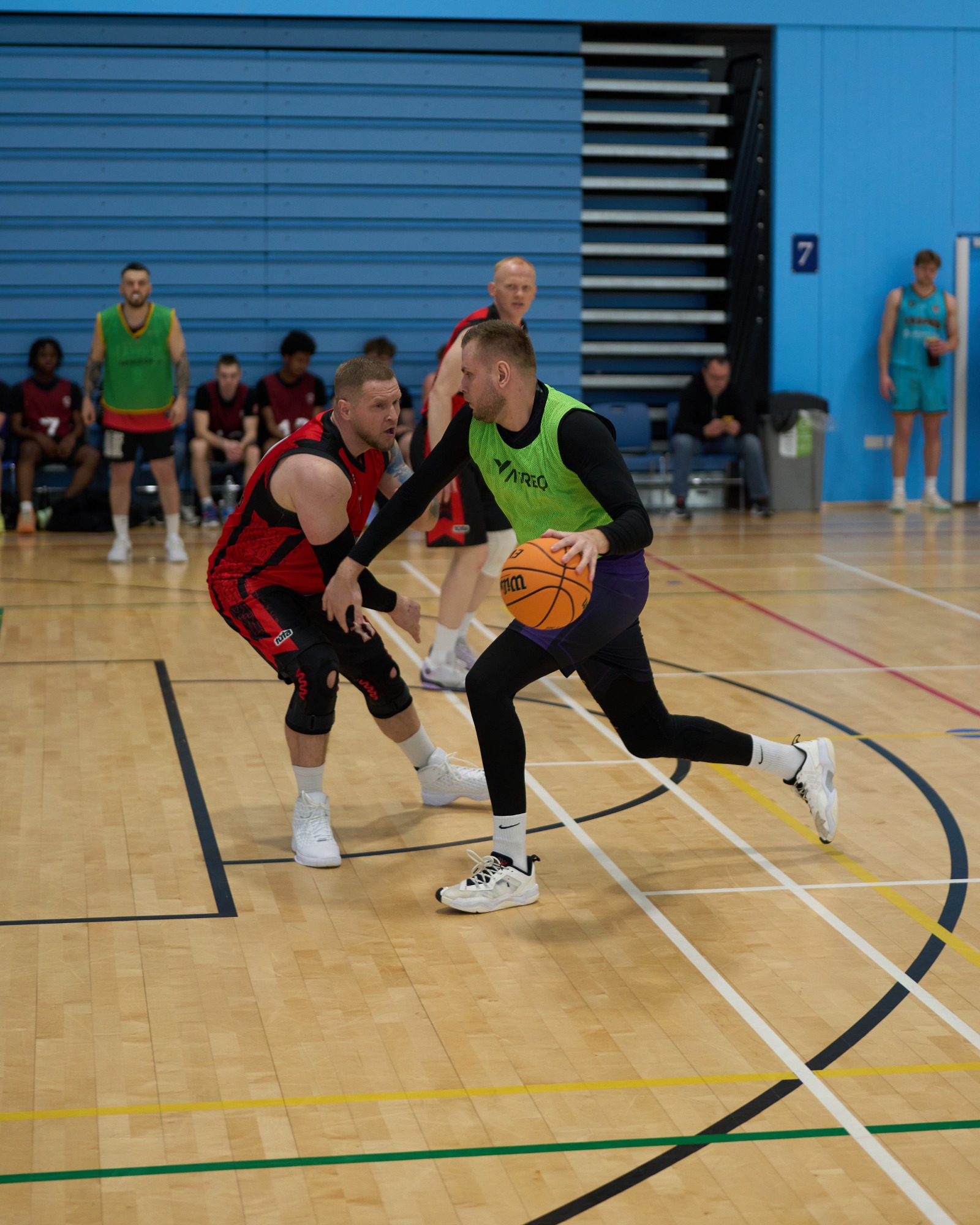 Side on view of basketball player driving into the key, whilst being defended.