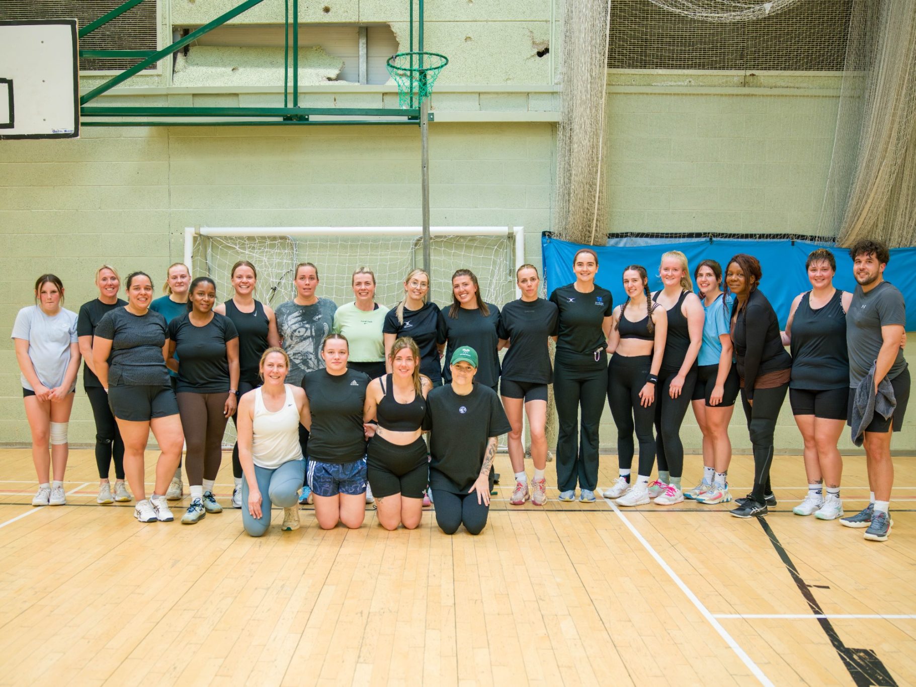 A group of diverse people posing together in a gymnasium.