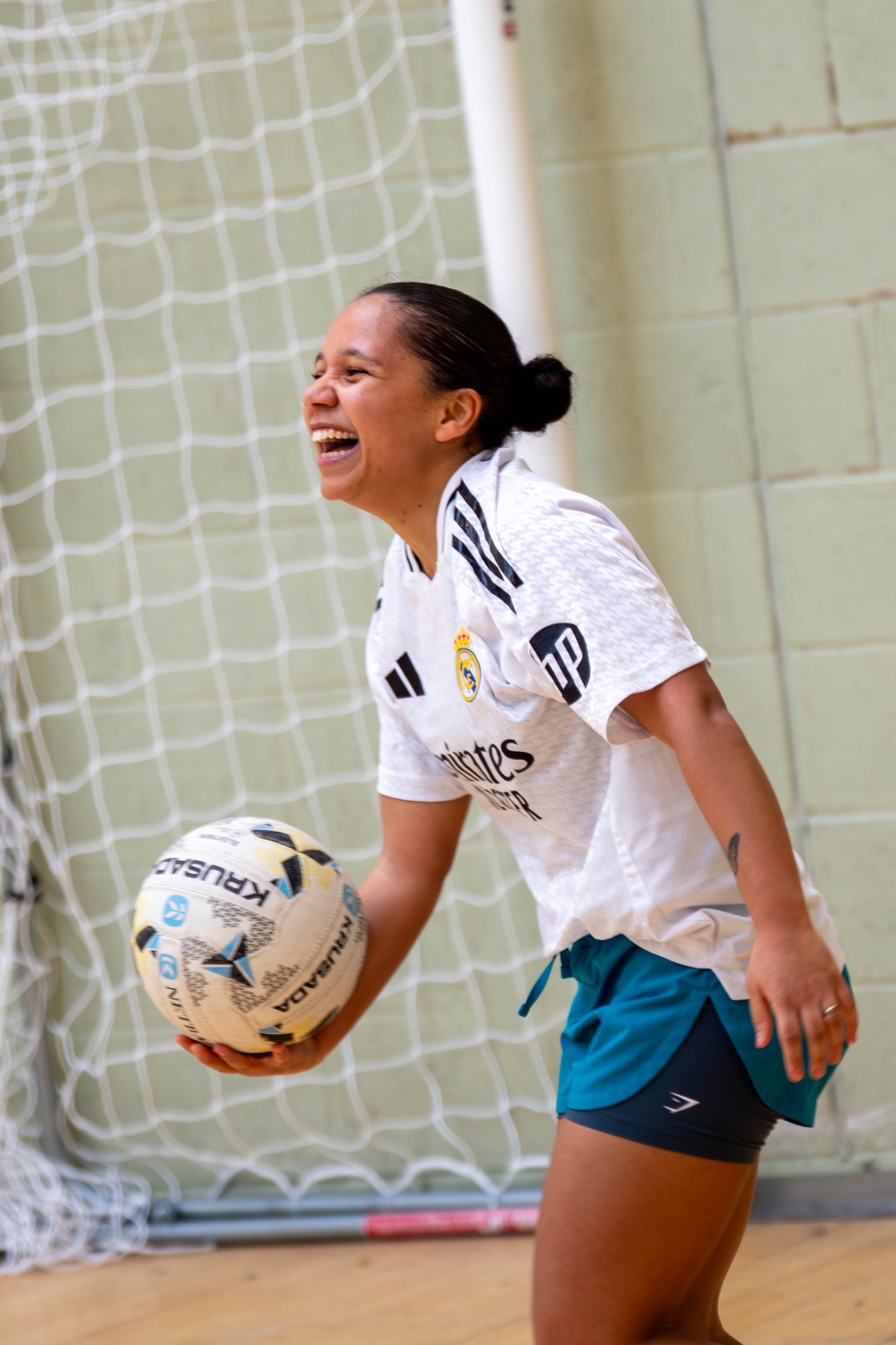 Female player laughing while holding a ball in an indoor sports gym.