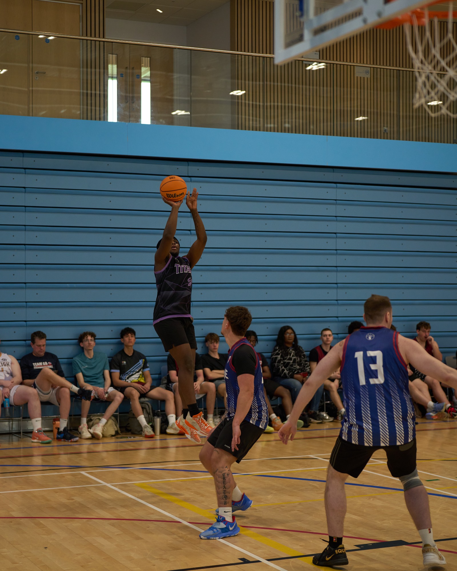 A player shoots a basketball while two opponents defend during a match.