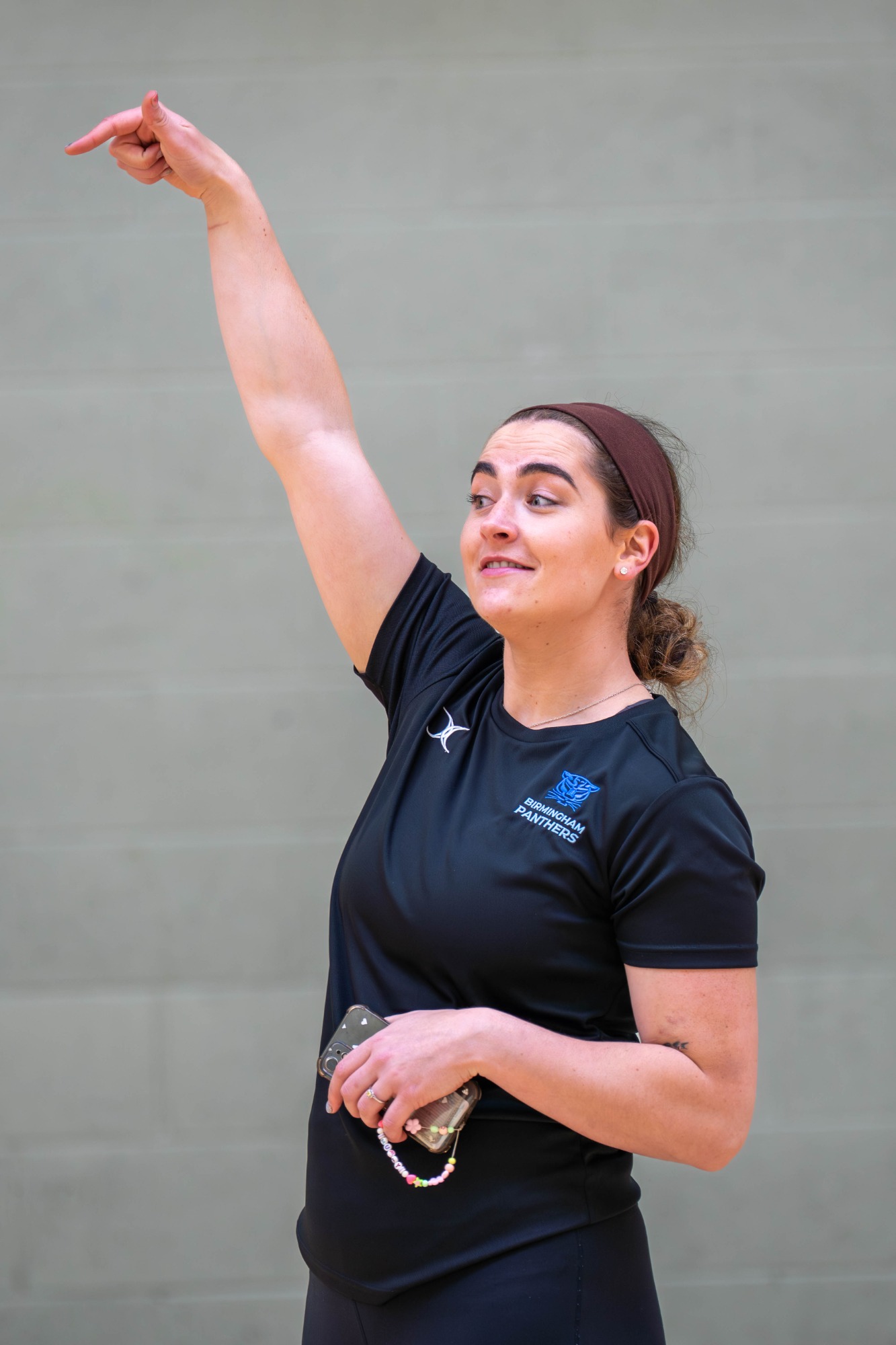 Athlete in a black shirt raising her arm while smiling.
