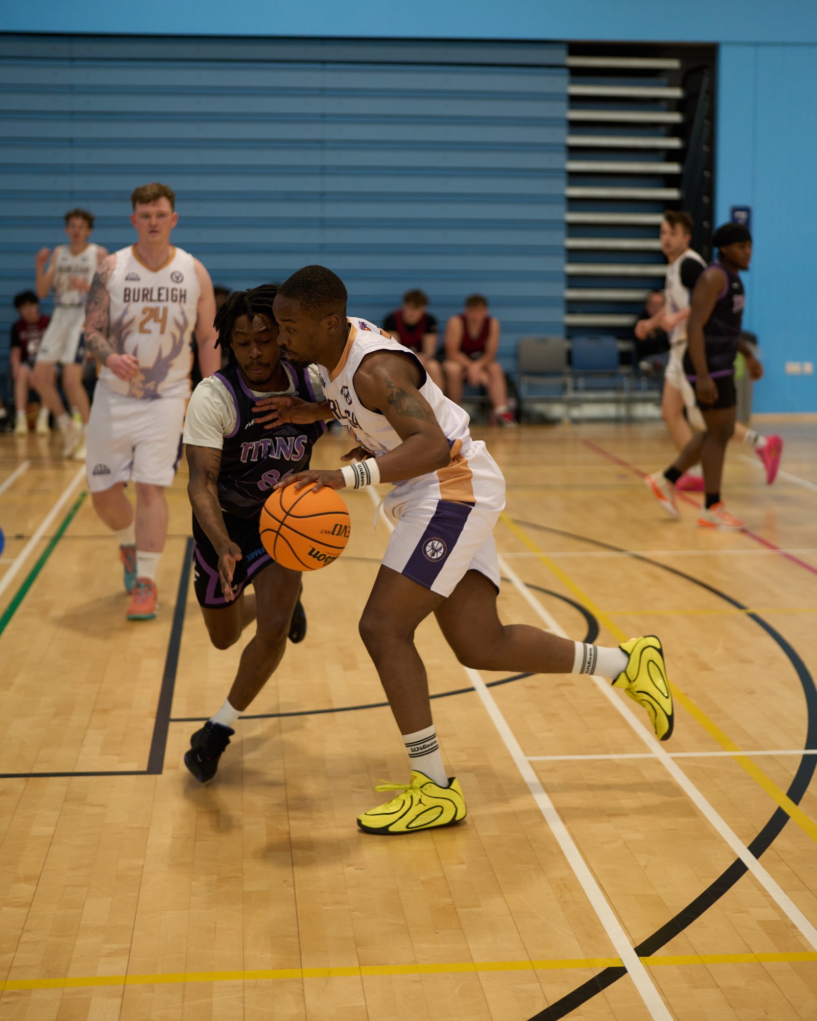 Side on of a defender reaching across to steal the basketball from another player.