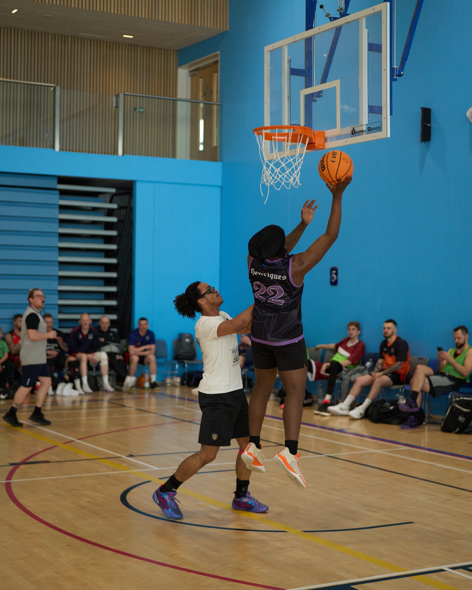 A basketball player attempts a jump shot while another defends closely.
