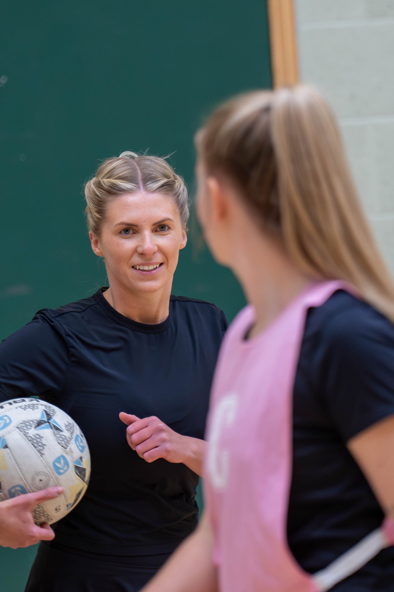 A coach demonstrating netball to a player in a training session.