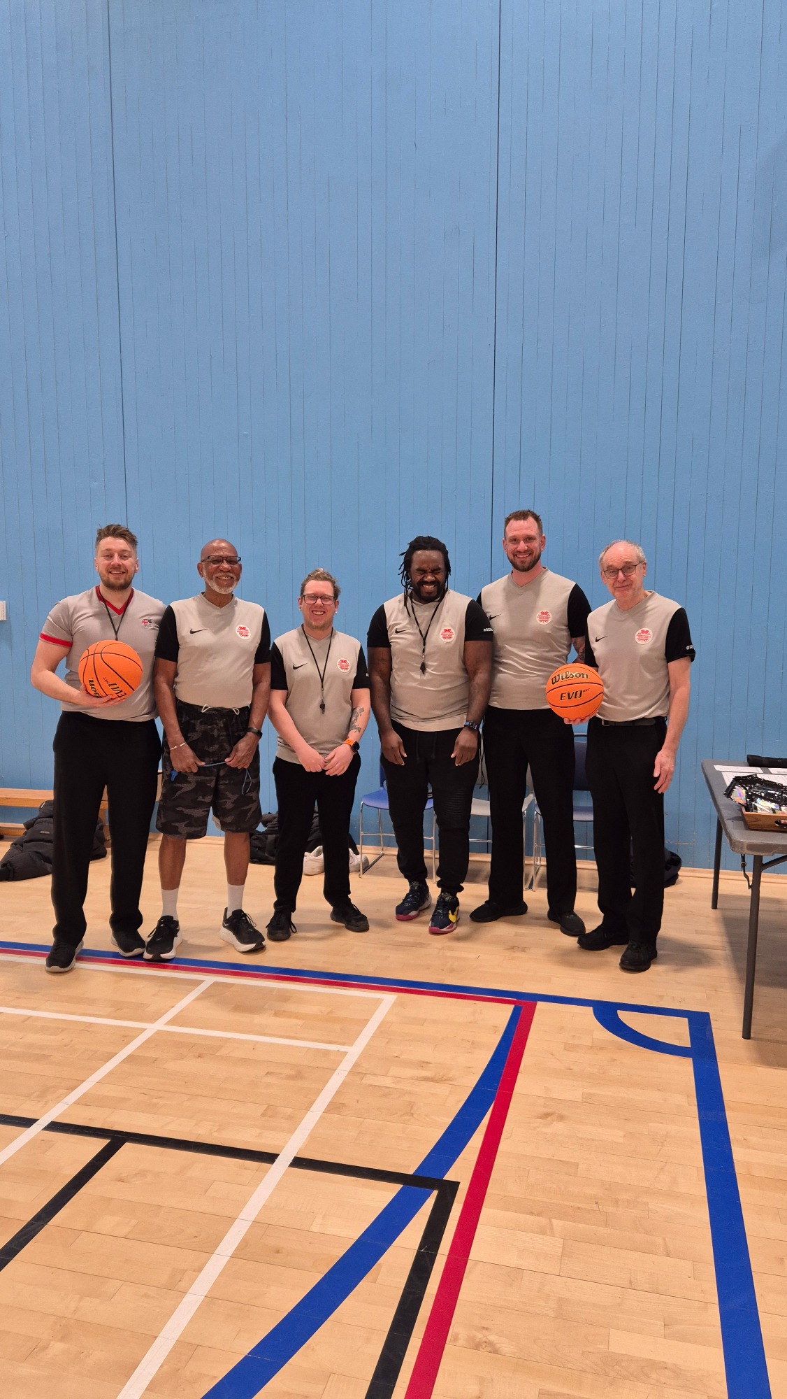 Team Referee A group of six basketball referees standing together in a gym, holding basketballs.