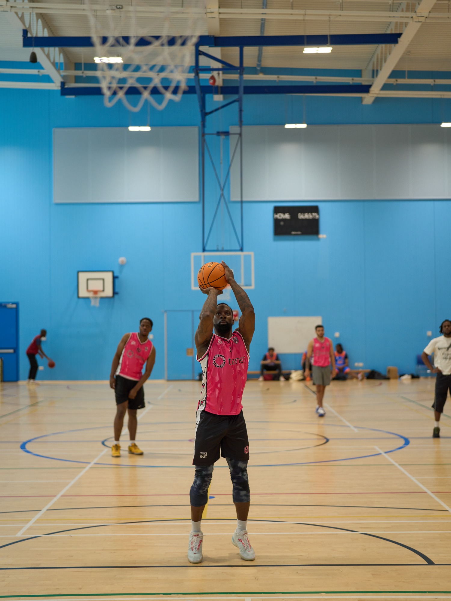 A basketball player prepares to shoot while others watch in the background.
