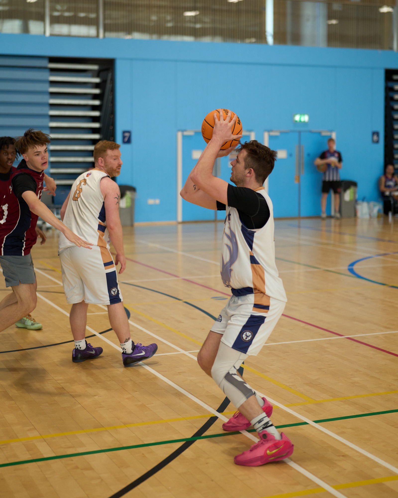 Basketball player preparing to shoot at a court with teammates and opponents nearby.