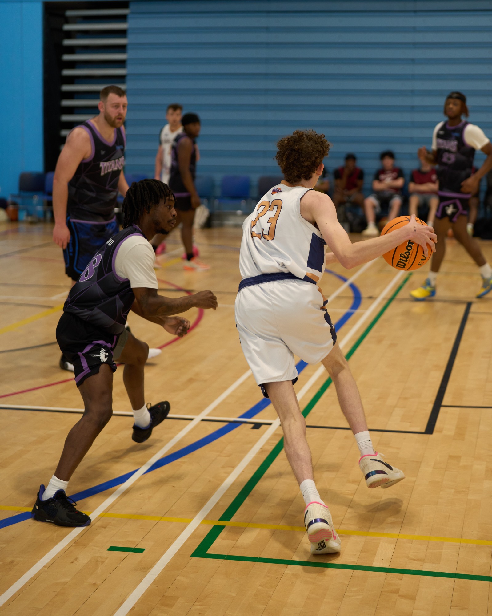 Shot from behind basketball player dribbling against an opponent.
