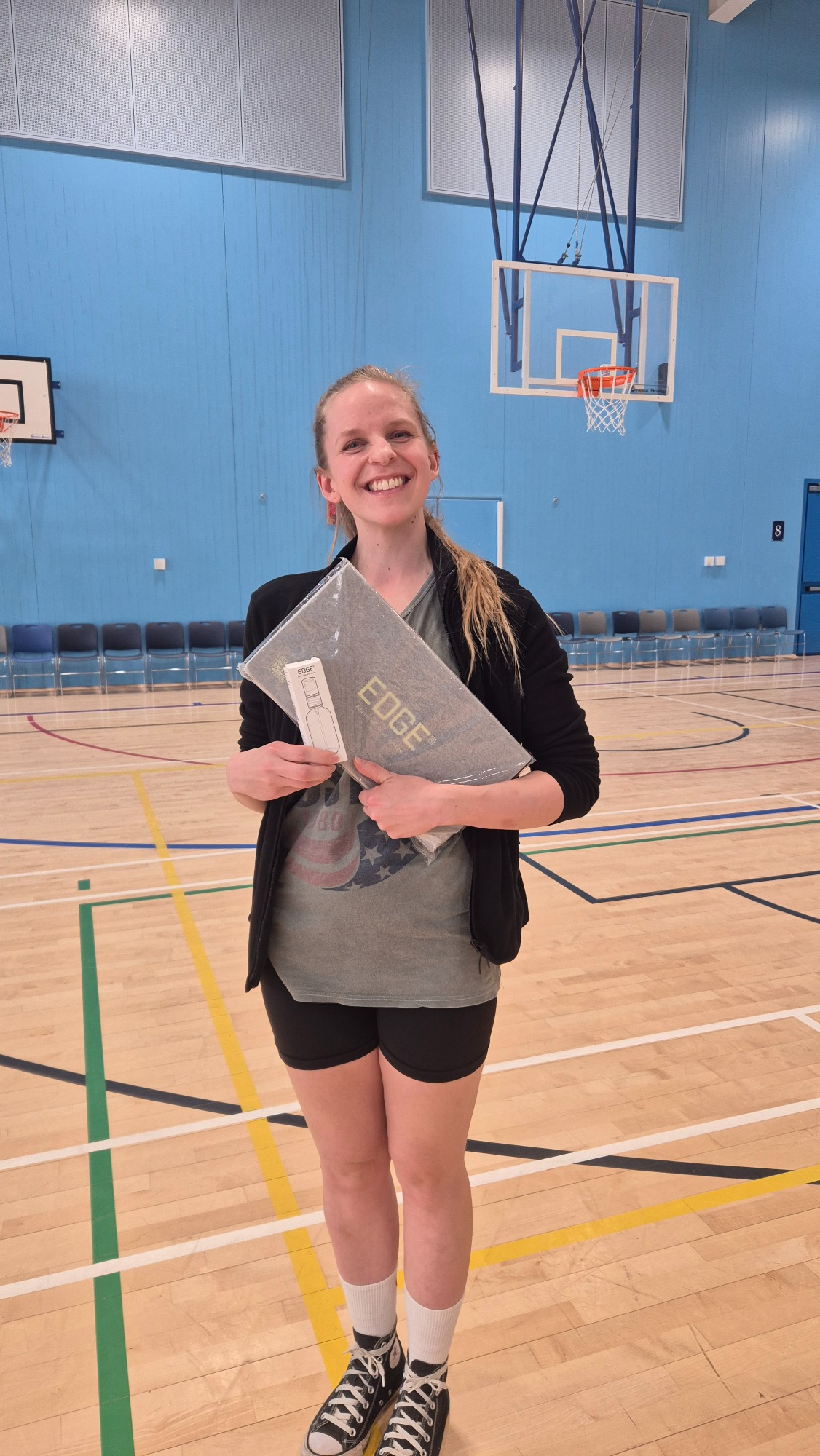 Edge Energy Winner: Ronin's Basketball Person smiling, holding a slip mat in a sports hall with a basketball court in the background.