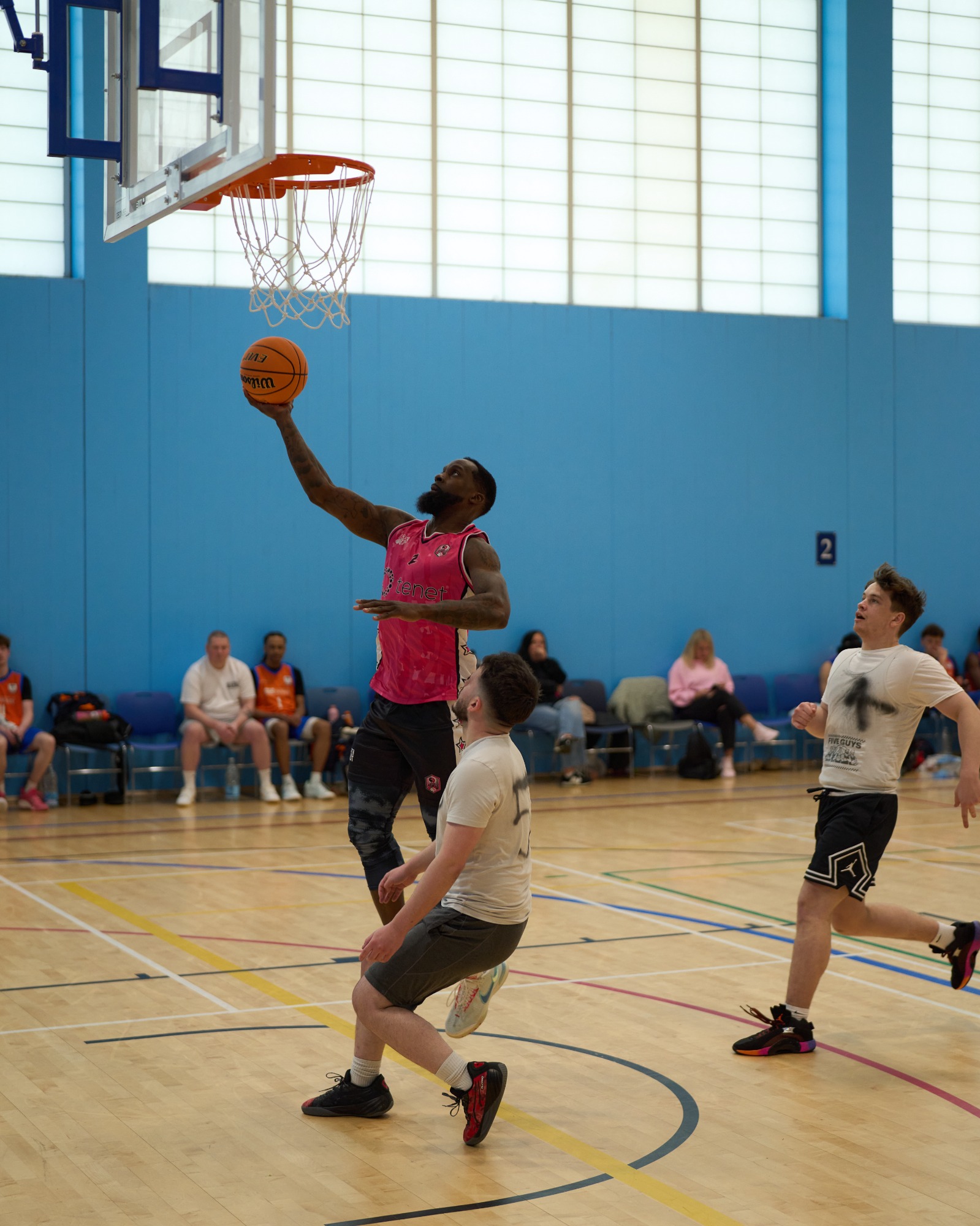 A player in a pink top makes a layup while another player defends.