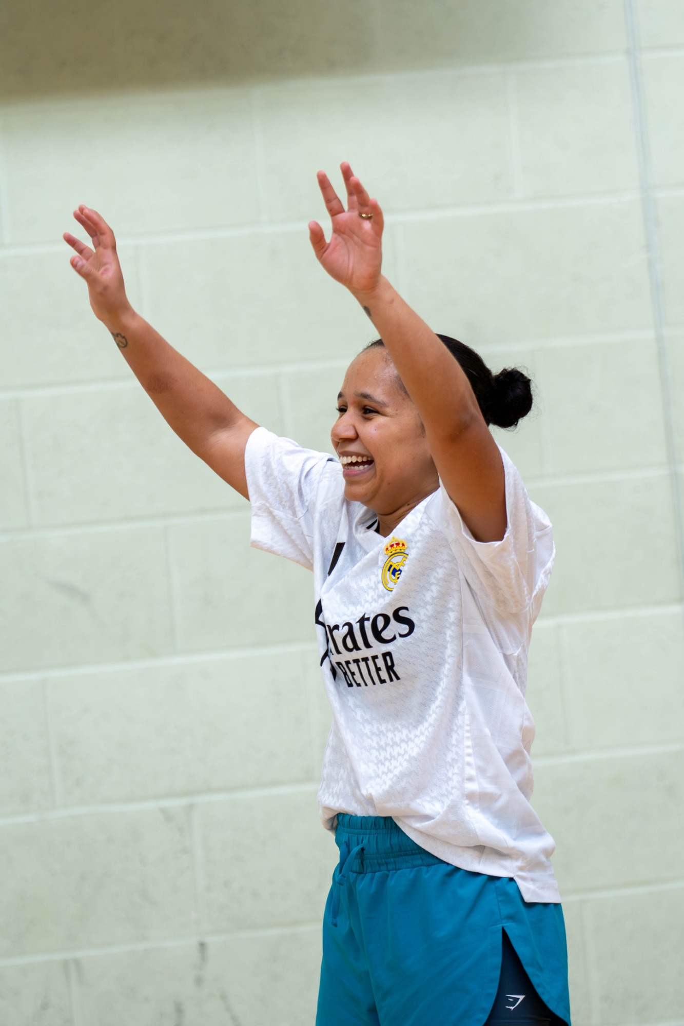 A woman celebrates with raised arms while wearing sports attire.