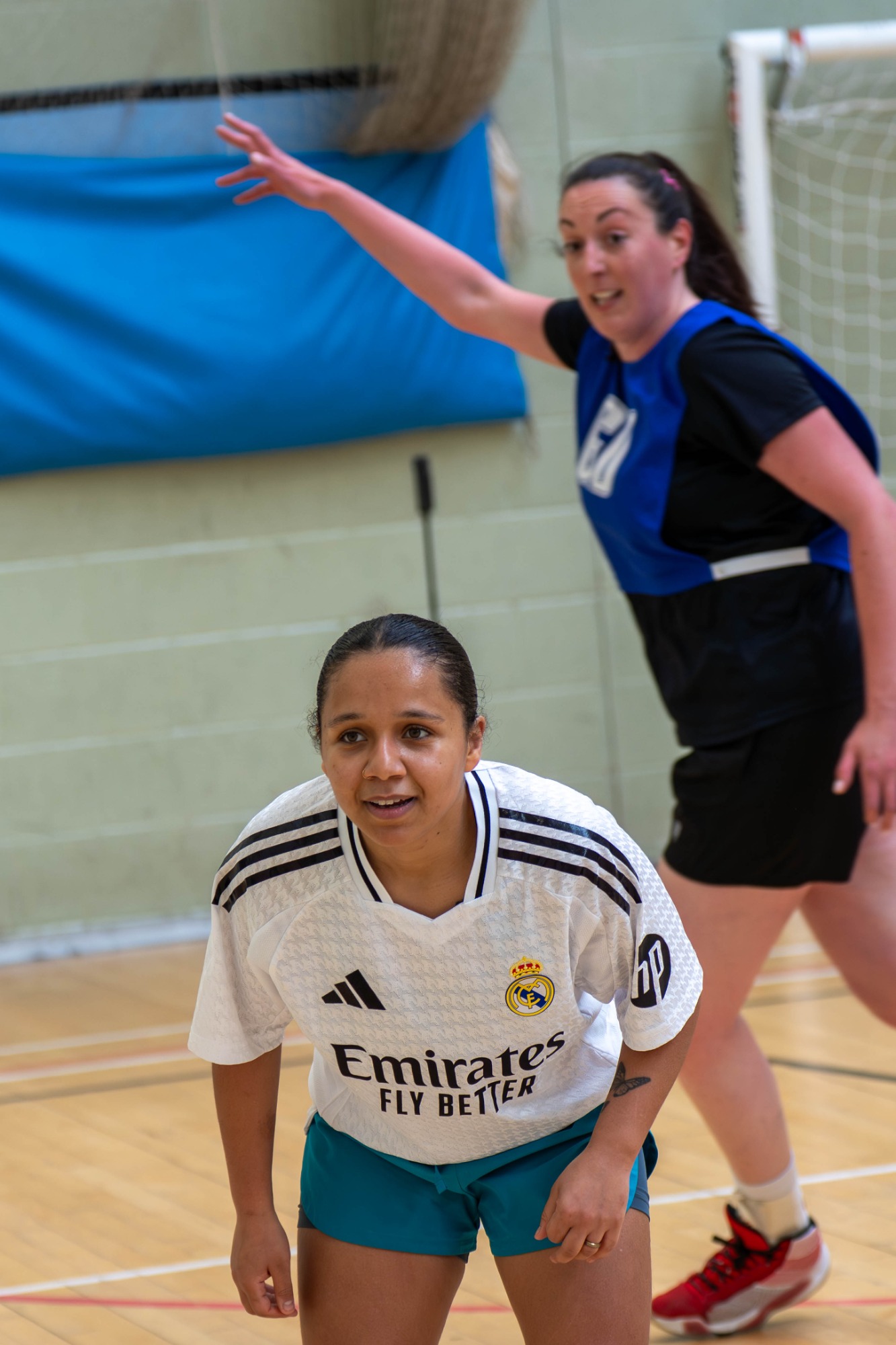 Two women engaging in a sports game, one aiming to pass the ball while the other defends.