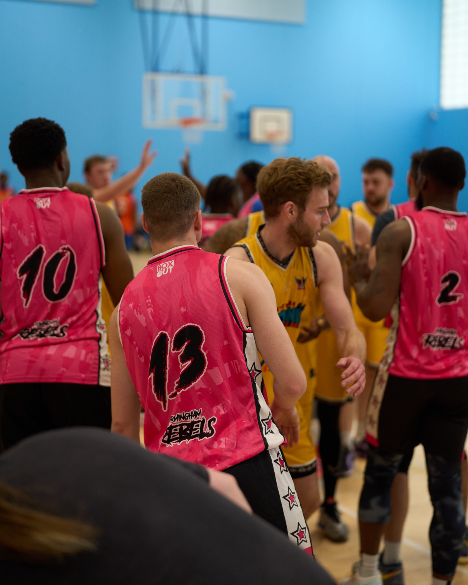 Players shaking hands and high fiving after a basketball match.