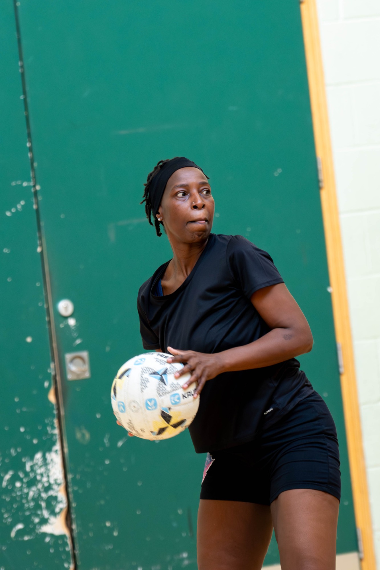 Woman in a black outfit prepares to throw a ball in a sports hall.