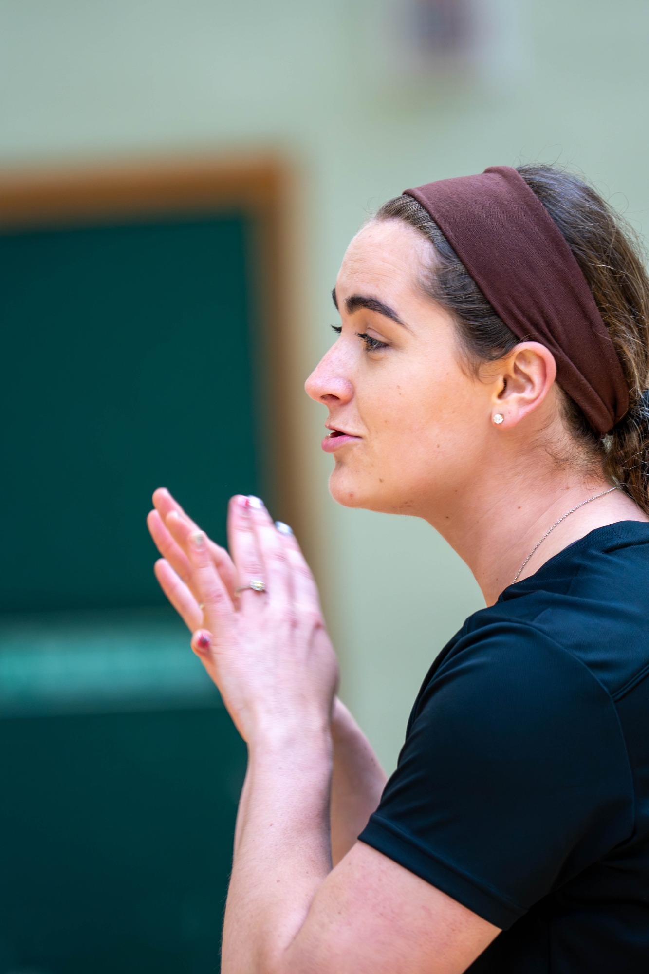 A woman in a sports top gestures while speaking, focusing intently.