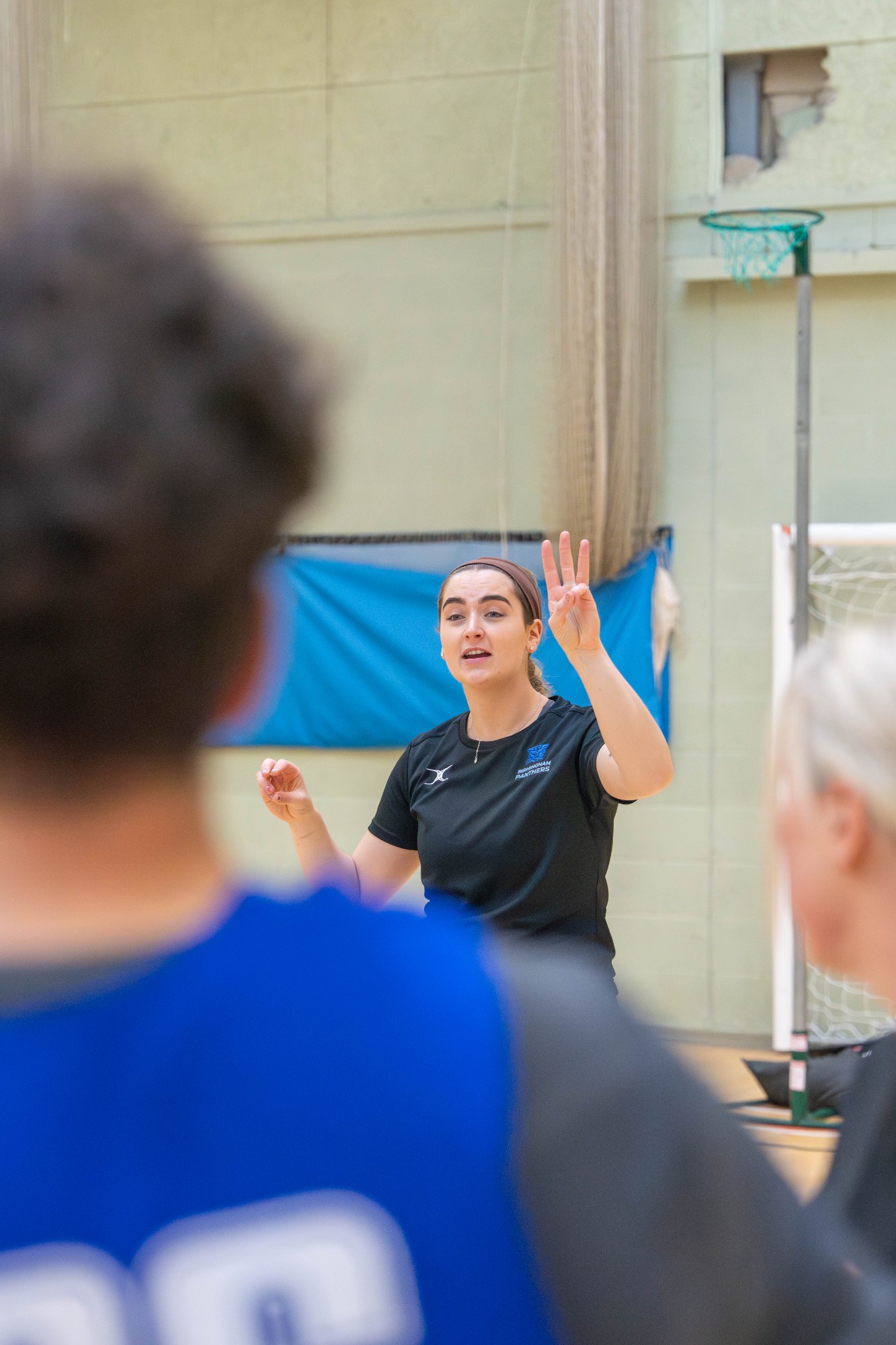 A coach gestures and speaks to basketball players during practice.