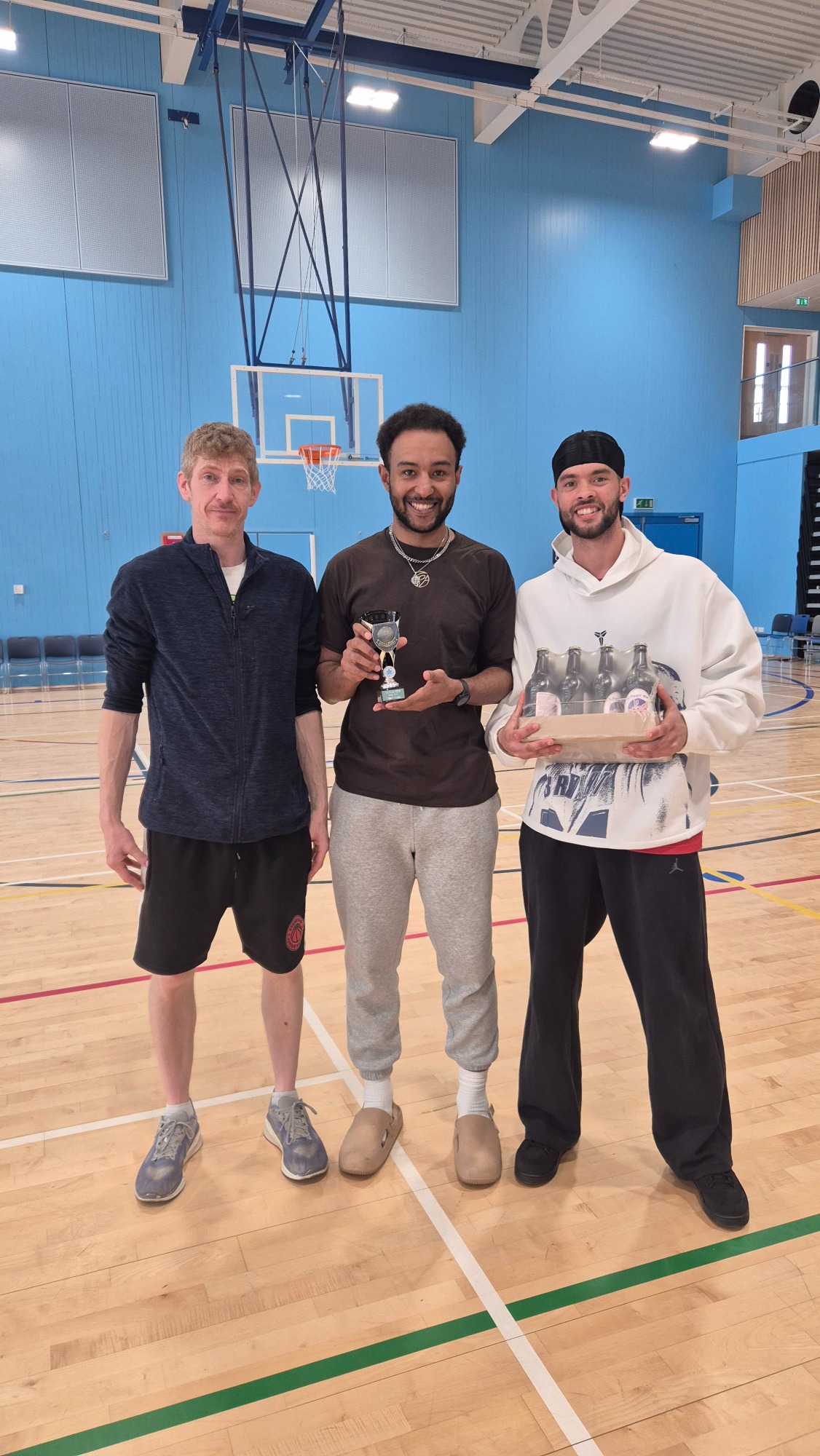 Team Vibes Award: Peterborough Panthers Three men standing in a gymnasium, each holding a trophy, smiling at the camera.