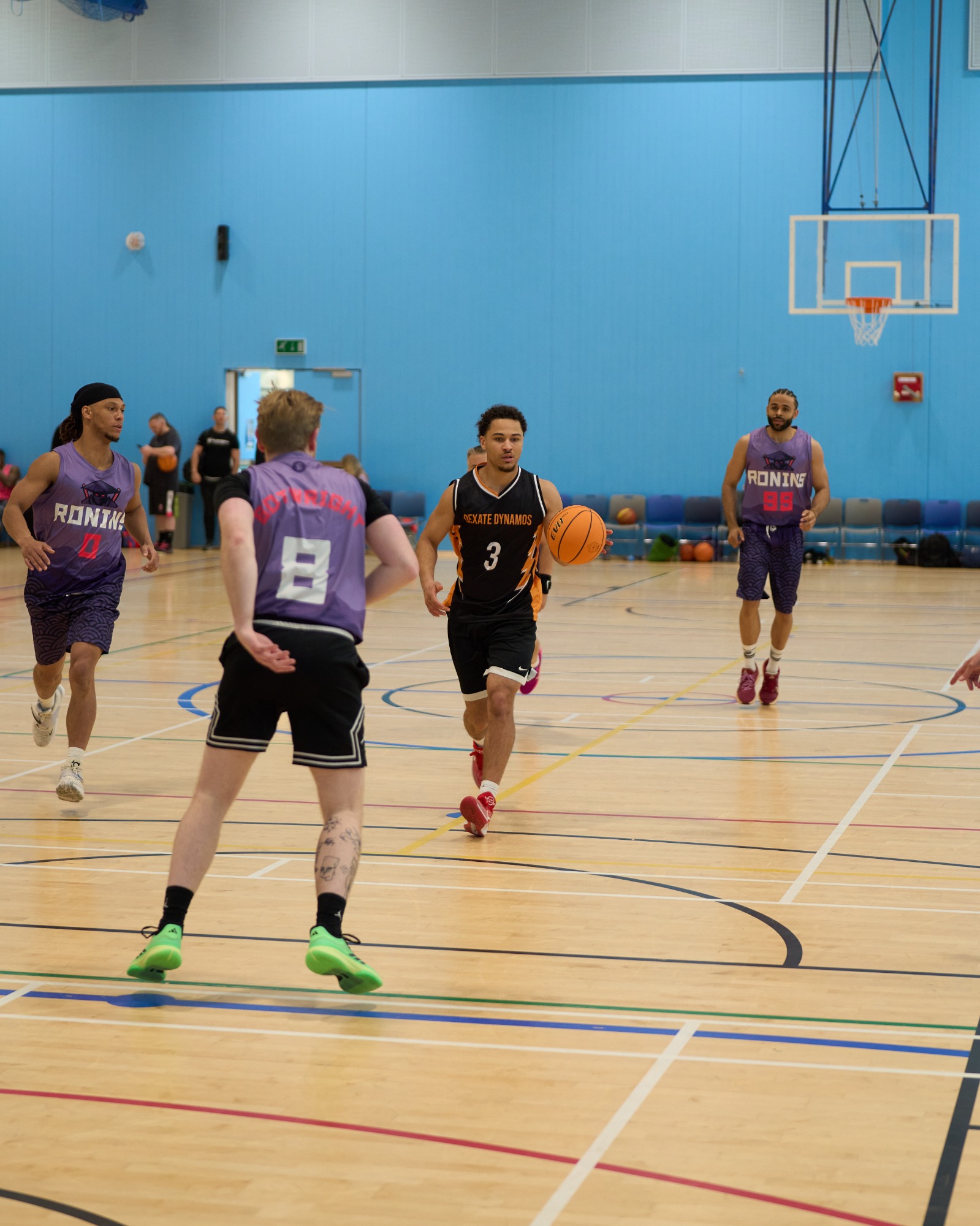 Player dribbling the ball in the midcourt with 3 defenders around them.