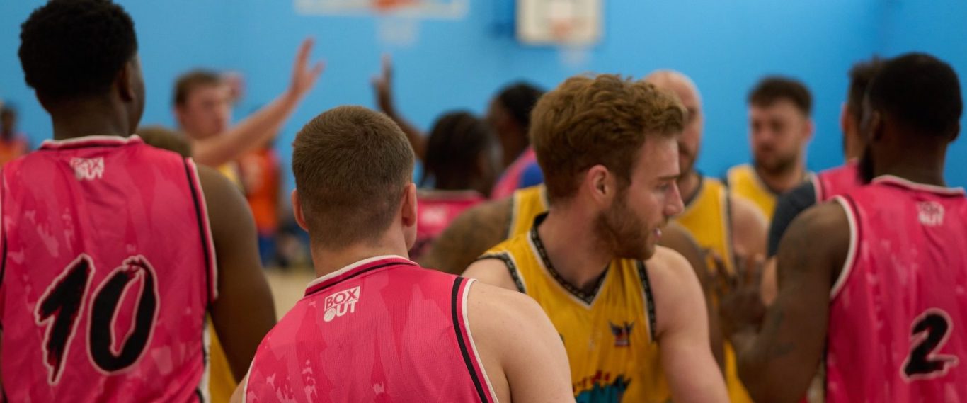 A group of basketball players in brightly coloured jerseys during a game.